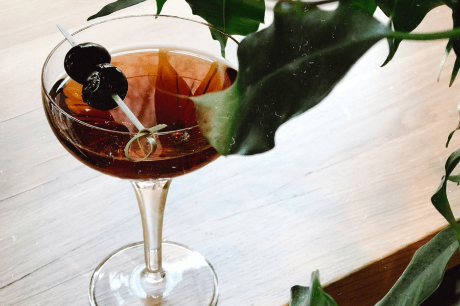 Affinity Cocktail on table garnished with cherries