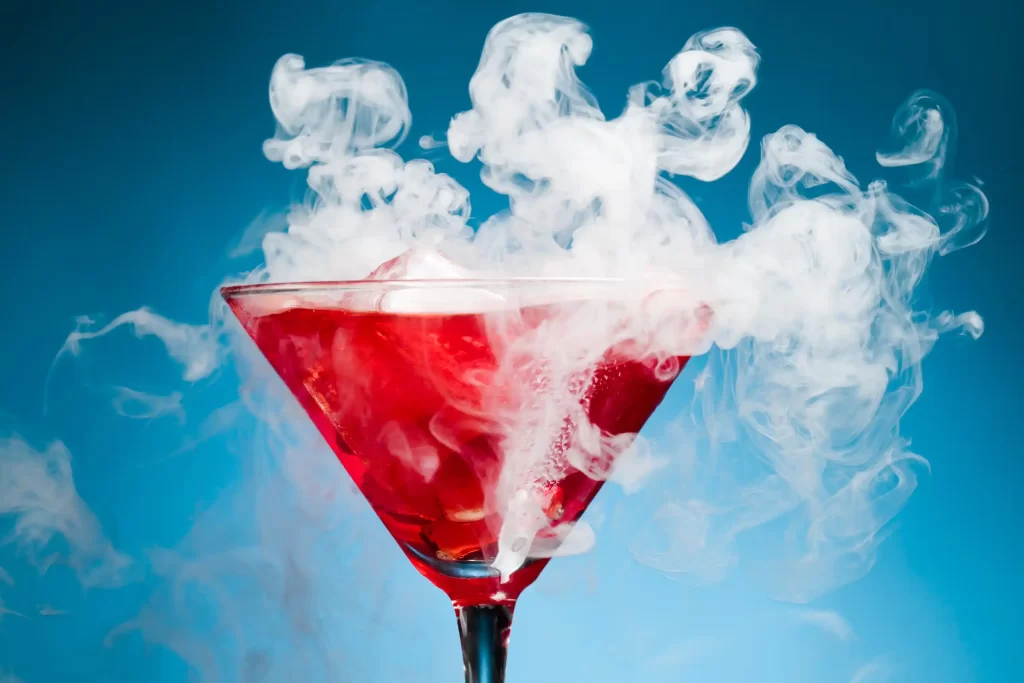 red drink in a martini glass with smoke billowing out of the glass