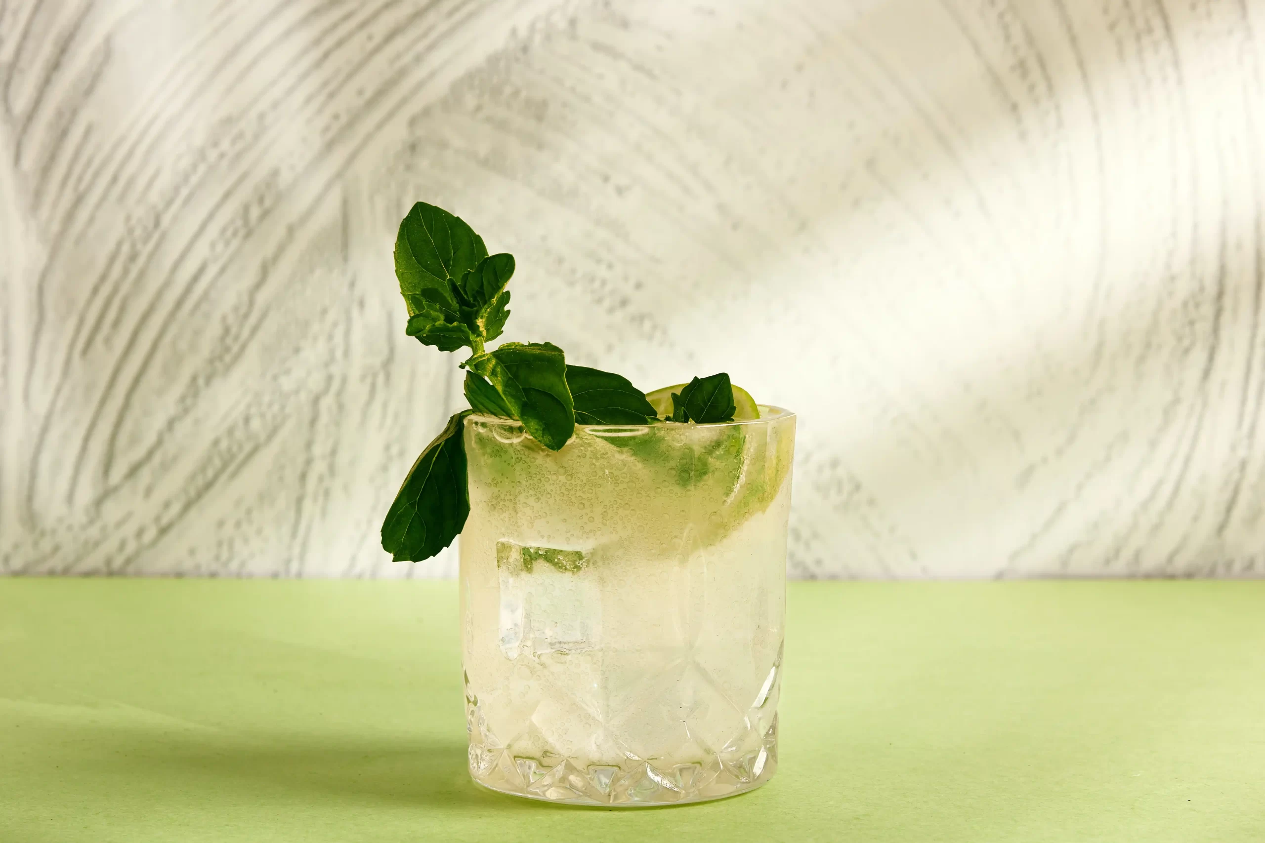Old Maid cocktail with mint garnish on green tabletop with white background